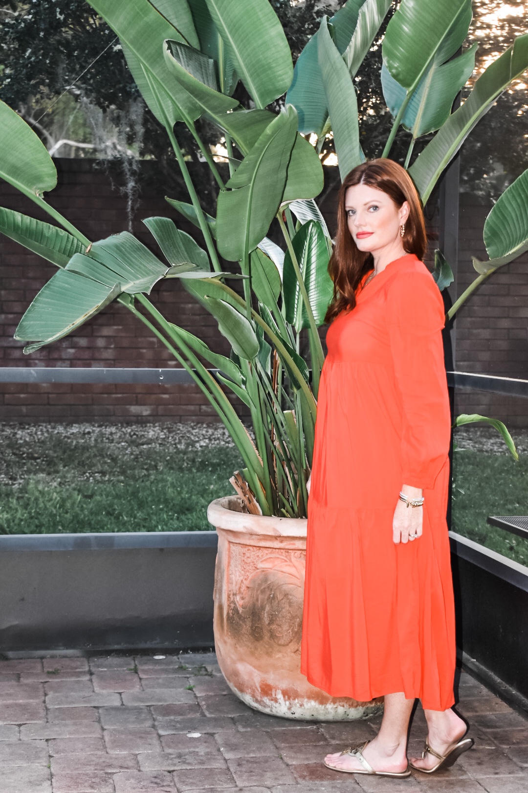 Lydia recreating Brigitte Bardot's 1970s summer style, wearing a red maxi dress and gold leather sandals.